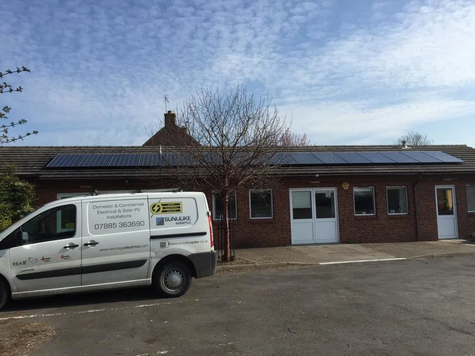 The Scoop Electrical Services van outside a single-storey building with a row of solar panels on its roof